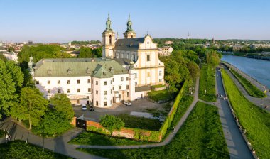 Krakow, Polonya. Skalka Kilisesi ve Paulinite Manastırı ve Vistula Nehri. Seçkin Polonyalıların tarihi gömme yeri. Duvarlarda yürüyen ve oturan insanlarla bulvarlar. Bahar, gün batımı