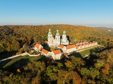 Bielany, Krakow, Polonya 'daki tepedeki bir ormanda aktif Camaldolese manastırı ve barok kilisesi, sonbahar renklerinde günbatımında hava manzarası
