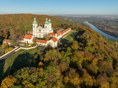 Bielany, Krakow, Polonya 'daki tepedeki bir ormanda aktif Camaldolese manastırı ve barok kilisesi. Günbatımında hava manzarası Vistula Nehri ile sonbaharda ve arka planda Krakow şehrinin uzak manzarası