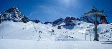 Avusturya Alplerinde kayak pistleri, teleferik teleferikleri, kayakçılar ve snowboardcular olan Stubai buzulları. Arka planda Schaufelspitze zirvesi