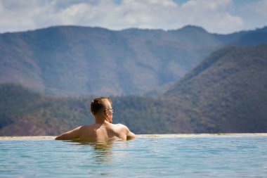 Beautiful landscape of natural infinity pool Hierve el Agua with young caucasian man relaxing, waterfalls Oaxaca, Mexico