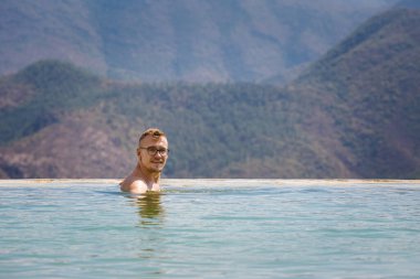 Beautiful landscape of natural infinity pool Hierve el Agua with young caucasian man relaxing, waterfalls Oaxaca, Mexico