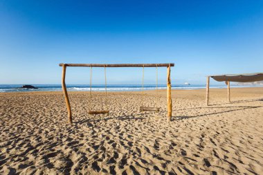 Beautiful Zipolite beach in Mexico. Swing on the blue sky
