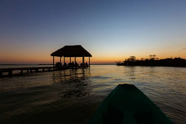 Group of people watching beautiful sunrise in Laguna Bacalar in Mexico. Photo taken during kayak trip.