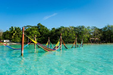 Beautiful white female tourist relaxing in a hammock in Laguna Bacalar in Mexico during kayak trip. clipart