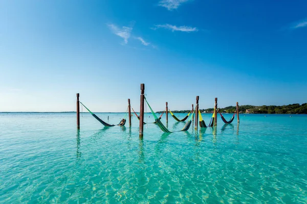 Beautiful white female tourist relaxing in a hammock in Laguna Bacalar in Mexico during kayak trip.