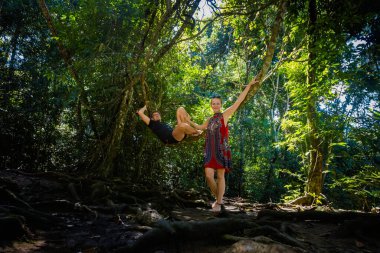 Roberto Barrios Cascadas parkında Palenque, Meksika 'da bir ağaçta oturan genç ve güzel bir çift. Güneşli bir günde yemyeşil renkli canlı manzara fotoğrafı.