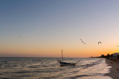 Gün batımında Meksika 'daki güzel Progreso plajı. Romantik beyaz plaj ve denizde bir tekne