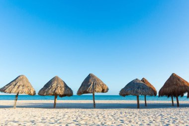 Güneşli bir günde Meksika 'daki güzel Progreso plajı. Beyaz sahilde doğal şemsiyeler ve mavi gökyüzü.