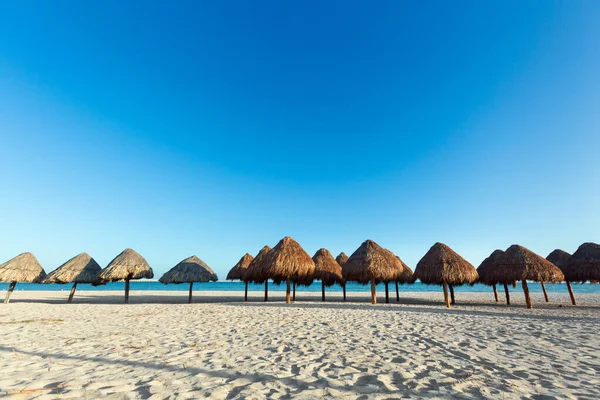 Güneşli bir günde Meksika 'daki güzel Progreso plajı. Beyaz sahilde doğal şemsiyeler ve mavi gökyüzü.