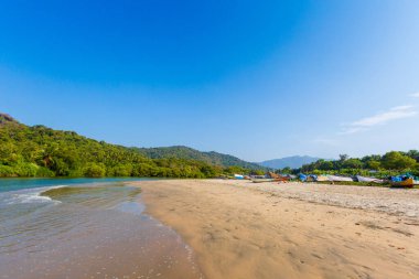 Goa, Hindistan 'da ünlü Palolem plajında mavi gökyüzü ve tekneyle çekilmiş güzel manzara fotoğrafı..