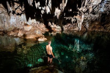 Young handsome man in Dzalbay, Sac Aua cenotes in Mexico, Valladolid area. Vivid landscape photo with lush green and crystal water