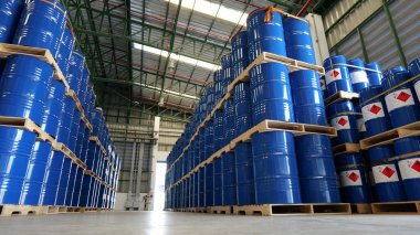 Depoda mavi bir fıçı, 200 litrelik kimyasal variller ahşap paletlere yerleştiriliyor ve teslimatı bekliyor. Ulaşım teknolojisi, petrol endüstrisi ve kimya endüstrisi kavramları