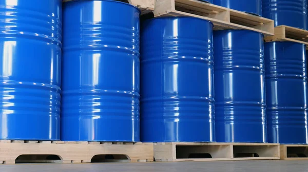 Blue barrel 200 liter chemical drums are stacked on wooden pallets inside the warehouse awaiting delivery. Concept of Chemical industry, petroleum industry and transportation technology