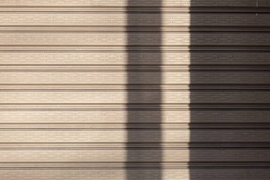 Doğal ışık tarafından oluşturulan soyut gölgeli gri renkli metal kapı tasarım, inşaat ve mimari projeler için uygun modern bir endüstriyel arkaplan oluşturuyor..