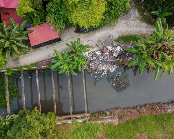 Aerial top down view rubbish is thrown beside the river near rural area