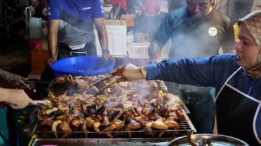 Gurney, Penang, Malezya - 28 Ağustos 2022: Hawkers çelik ızgarada tavuk kanadını kızarttı