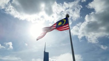 Aerial tracking Malaysia flag at Dataran Merdeka with background of PNB118 tower in blue sunny sky