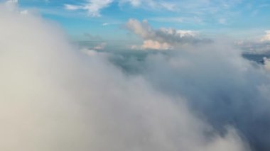 Mavi, güneşli bir günde, beyaz bulutların üzerinde uçan bir hava.