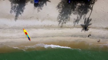 Aerial top down view banana boat with the shadow of coconut tree near the beach