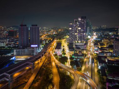 Bukit Bintang, Kuala Lumpur, Malezya - 28 Kasım 2022: Şehrin yolları ve otoyolları aydınlık bir şekilde aydınlatılmış, şehrin hareketli enerjisini gösteren büyüleyici ışık yolları deseni oluşturulmuştur.