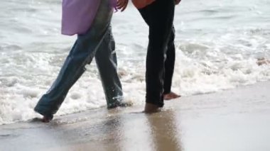 İki kişi sahilde deniz suyuyla yürür.