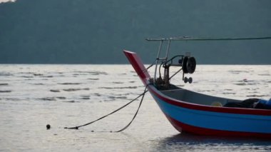 Yavaş çekim görüntüsü yumuşak dalga ve canlı mavi ve kırmızı tekne, köpüklü suda huzur içinde yüzüyor.