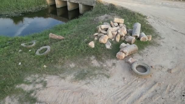 川の近くの道路の側面に岩やゴミのタイヤの山 — ストック動画