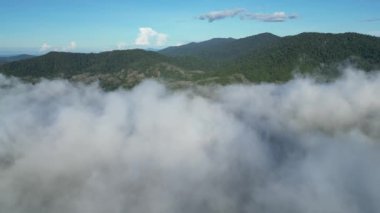 Alçak bulutlar ve uzak bir tepenin yer aldığı, bir sabah manzarasının cennet gibi cazibesini resmeden hava sahnesi.