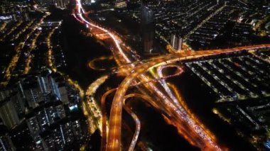 Şehir ışıklarının atmosferik parıltısını sinir bozucu trafik sıkışıklığının ortasında gösteren yüksek açılı perspektif.