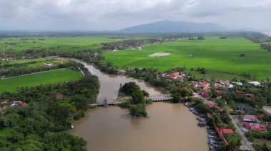 Bir nehir yeşil bir tarladan akıyor. Nehir kahverengi ve üzerinde Kuala Sala, Kedah 'da bir köprü var.