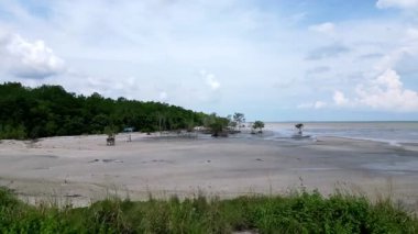 Arka planda küçük bir su kütlesi olan bir plaj. Kumsal ağaçlarla çevrili. Hava manzaralı Pantai Perpat, Batu Pahat