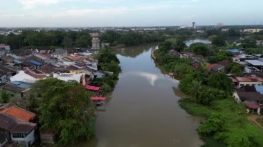 Alor Setar, Kedah, Malezya - Jan 08 2024: Her iki tarafında evler olan bir kasabadan geçen bir nehir. Su kahverengi ve bulanık. Nehirde yüzen birkaç tekne var.
