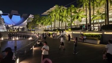 Marina Sand, Singapur, 0 - 17 Temmuz 2024: Turistler Marina Körfezi Kum Güvertesi 'nde akşam ışıklarının altında geziniyorlar.