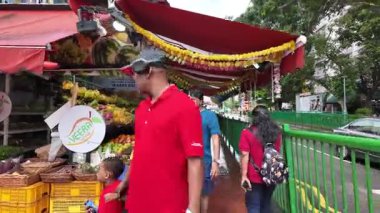 Singapore - Jul 09 2024: A man in a red shirt is walking near fruit market