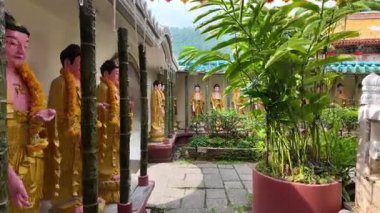 Ayer Itam, Penang, Malaysia - Feb 04 2024: A row of statues of Buddha are lined up in a courtyard. The statues are made of wood and are arranged in a row