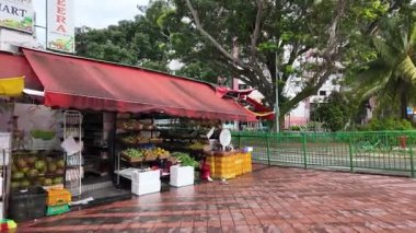Singapore - Jul 09 2024: A man is walking in front of a fresh market. The market is selling fruits and vegetables