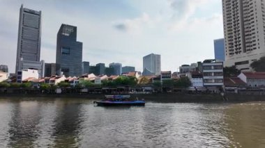 Singapore - Jul 17 2024: A boat is floating on Singapore River in front of a city