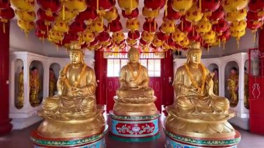 Ayer Itam, Penang, Malaysia - Feb 04 2024: Three statues of Buddha are sitting on pedestals in a room at Kek Lok Si Temple