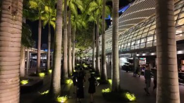 Marina Bay, Singapore - Jul 09 2024: A group of people walk down a walkway in a shopping mall at Marina Bay Sand. The walkway is lit up with lights