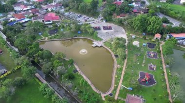 Batu Pahat, Johor, Malaysia - Jun 03 2024: A park with a pond and a playground. The pond is surrounded by trees