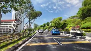 Bukit Bintang, Kuala Lumpur, Malaysia - Jun 15 2024: A blue car is driving down a street with a yellow line.