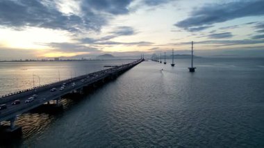 Gelugor, Penang, Malaysia - Jun 20 2024: Penang Bridge with a sunrise in the background. The bridge is busy with cars and trucks
