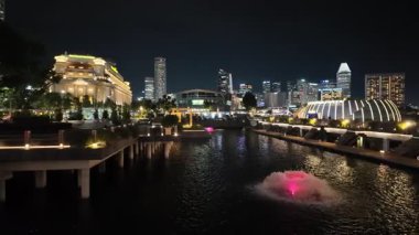 Marina Bay, Singapore - Jul 09 2024: A city with a fountain in the of it. The fountain is pink and has a lot of lights around it