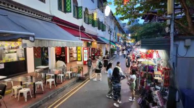 China Town, Singapore - Jul 10 2024: A group of people walk down a street with awnings and tables at China Town