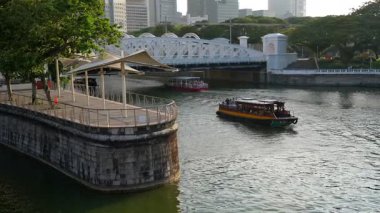 Marina Sand, Singapore - Jul 17 2024: A boat is traveling down a Singapore River near a bridge. The boat is yellow and is in the of the river