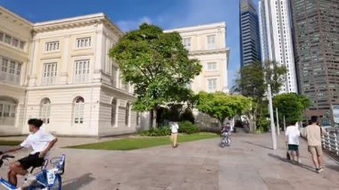 Singapore - Jul 17 2024: A group of people are walking down a sidewalk in front of a building