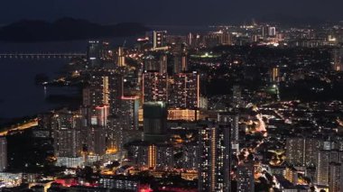 George Town, Penang, Malaysia - Dec 31 2024: City at night with a bridge in the background. The town is lit up with lights and the sky is dark