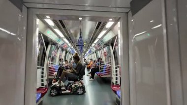 Changi, Singapore - Jul 16 2024: People sitting on a MRT train. They are both looking at their phones