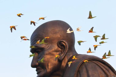 A flock of colorful parrots are flying past the Buddha statue. clipart